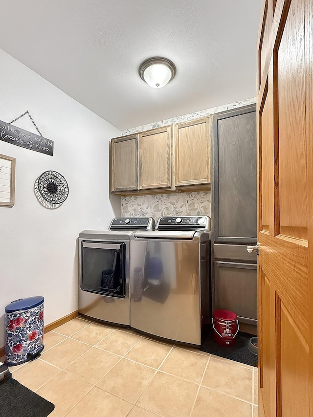 clothes washing area with cabinet space, independent washer and dryer, light tile patterned floors, and baseboards