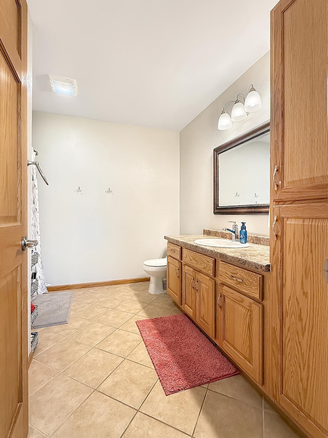 bathroom with tile patterned flooring, vanity, toilet, and baseboards