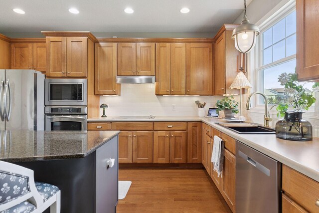 343 Primrose Path, Bayport, MN 55003 - kitchen featuring appliances with stainless steel finishes, a sink, under cabinet range hood, brown cabinetry, and recessed lighting