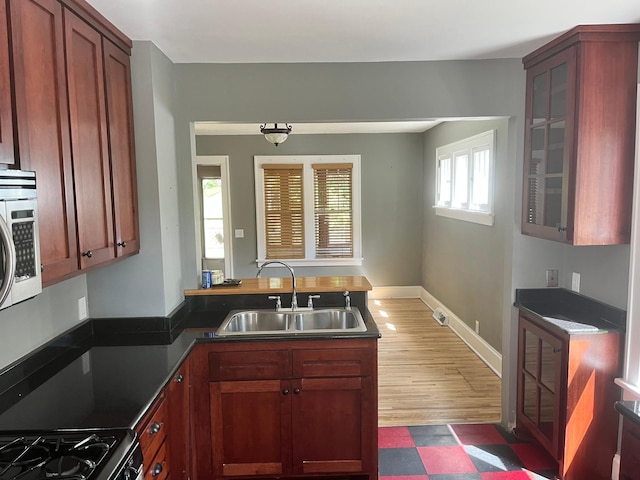 2748 41st Ave S, Minneapolis, MN 55406 - kitchen featuring a sink, a peninsula, gas range, glass insert cabinets, and dark floors