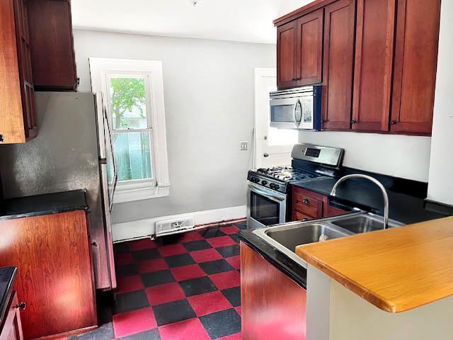 2748 41st Ave S, Minneapolis, MN 55406 - kitchen with stainless steel appliances, dark flooring, a sink, dark countertops, and a peninsula