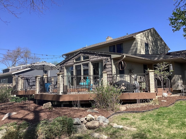 back of house featuring a wooden deck and a chimney