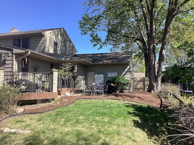 back of house with a lawn, a wooden deck, and a chimney