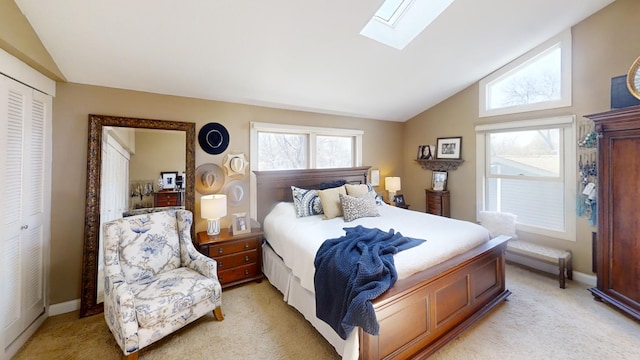 bedroom with lofted ceiling, a skylight, light carpet, a closet, and baseboards