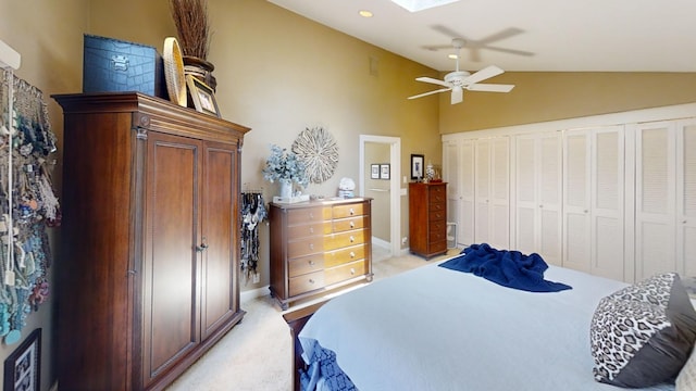 bedroom featuring light carpet, vaulted ceiling, a skylight, a ceiling fan, and baseboards