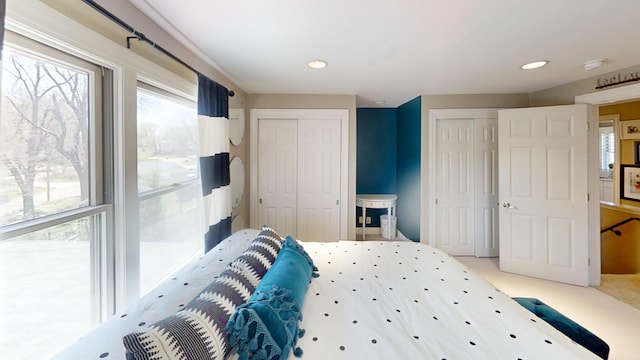 bedroom featuring two closets, multiple windows, recessed lighting, and light colored carpet