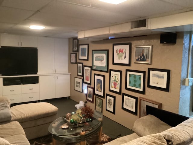 living area featuring a paneled ceiling and finished concrete flooring