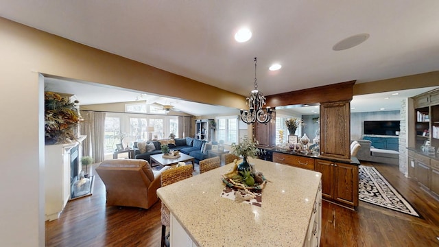 dining room featuring dark wood-style flooring, a fireplace, a chandelier, lofted ceiling, and a ceiling fan