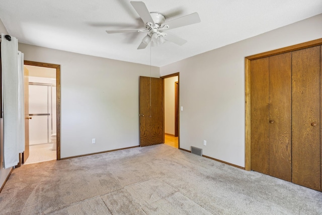 unfurnished bedroom with carpet flooring, a closet, baseboards, ensuite bath, and ceiling fan