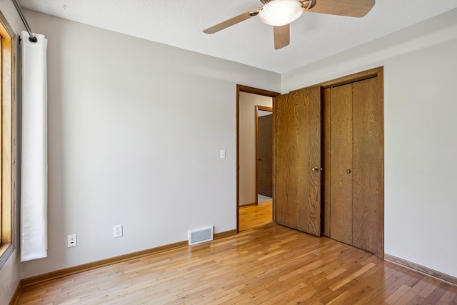 unfurnished bedroom featuring light wood finished floors, a closet, a ceiling fan, and baseboards