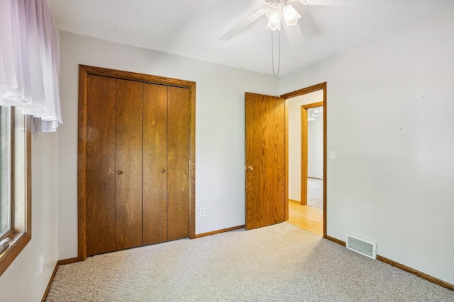 unfurnished bedroom with carpet floors, baseboards, a closet, and a ceiling fan