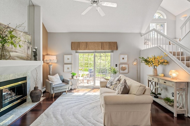living room featuring lofted ceiling, a ceiling fan, stairs, wood finished floors, and a baseboard heating unit