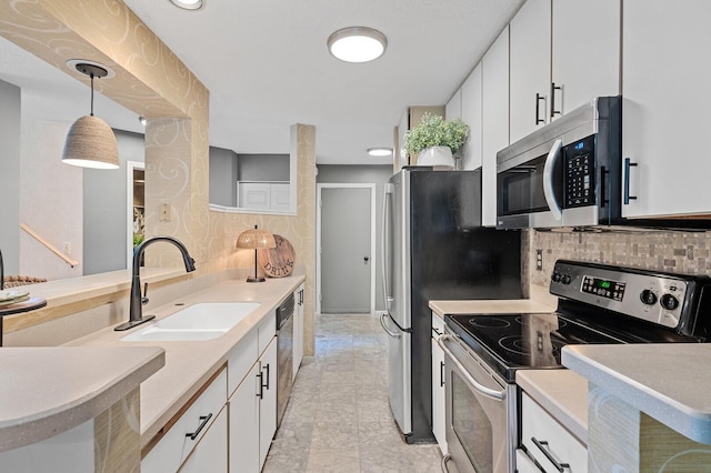 kitchen featuring stainless steel appliances, a sink, decorative backsplash, and white cabinetry