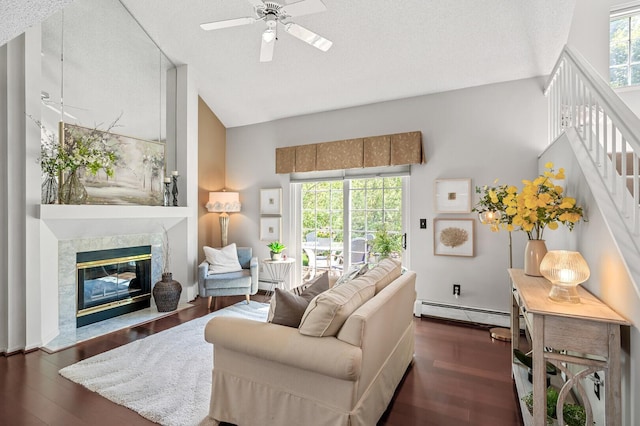 living room featuring a baseboard radiator, ceiling fan, dark wood-type flooring, a fireplace, and lofted ceiling