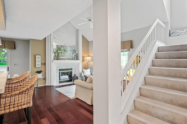 stairs with wood finished floors, ceiling fan, a fireplace, lofted ceiling, and baseboards