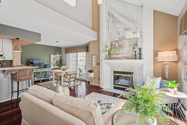 living room featuring dark wood finished floors, a premium fireplace, and ceiling fan