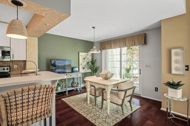 dining space featuring dark wood-style floors, baseboards, and a textured ceiling