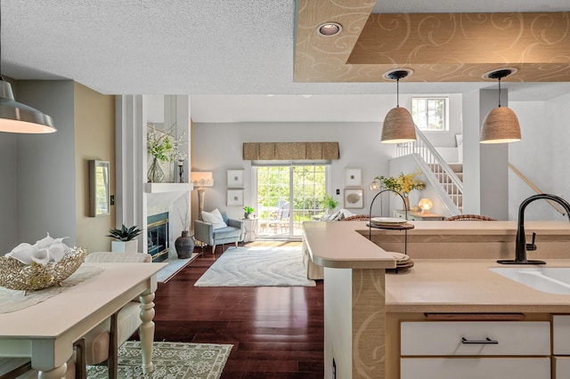 kitchen with a sink, plenty of natural light, light countertops, dark wood finished floors, and a textured ceiling
