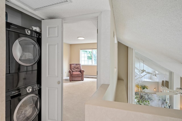 laundry room featuring stacked washer / dryer, a textured ceiling, carpet floors, and a baseboard heating unit