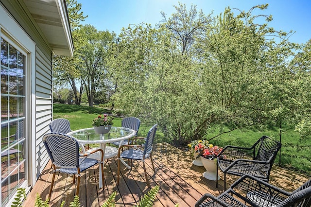 deck featuring outdoor dining space and a lawn