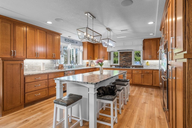 19776 214th Ave NW, Big Lake Twp, MN 55309 - kitchen with brown cabinetry, a breakfast bar, plenty of natural light, a textured ceiling, and recessed lighting