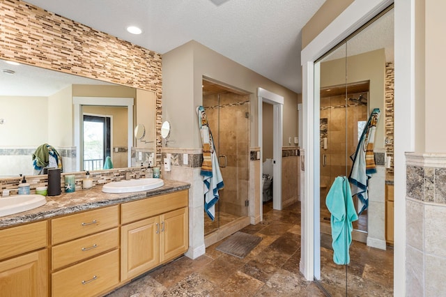 19776 214th Ave NW, Big Lake Twp, MN 55309 - full bathroom with tile walls, a shower stall, double vanity, a wainscoted wall, and a textured ceiling