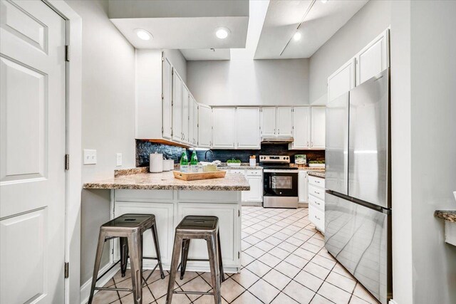 14716 Oak Run Ln, Burnsville, MN 55306 - kitchen with appliances with stainless steel finishes, a peninsula, decorative backsplash, white cabinetry, and light tile patterned floors