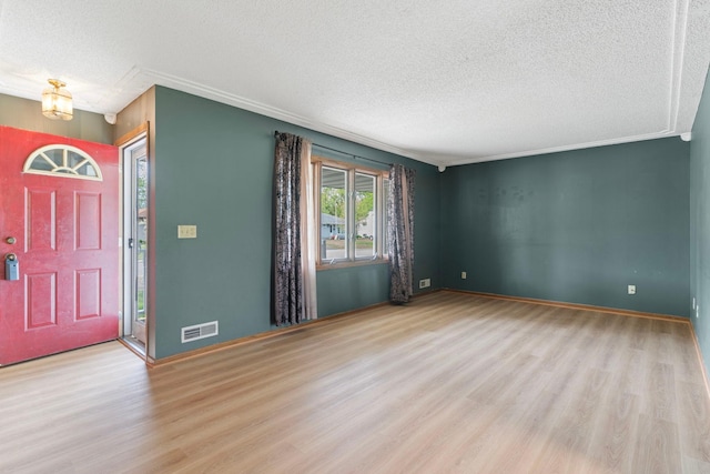 foyer entrance with a textured ceiling, wood finished floors, baseboards, and ornamental molding