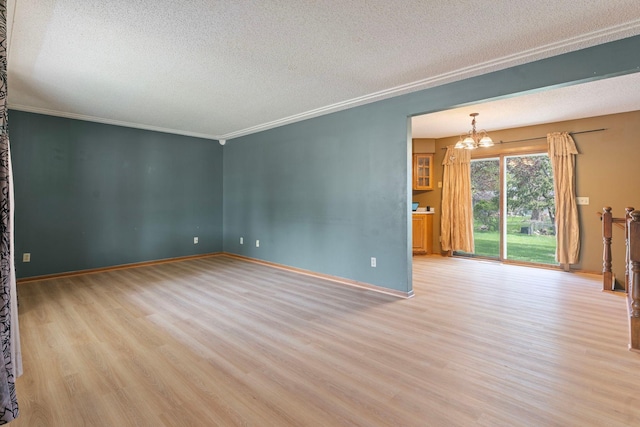 unfurnished living room featuring a textured ceiling, a chandelier, wood finished floors, baseboards, and ornamental molding