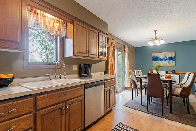 kitchen with dishwasher, brown cabinets, a sink, light countertops, and light wood-style flooring