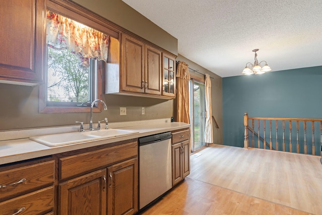 kitchen featuring dishwasher, a sink, brown cabinets, light countertops, and a textured ceiling