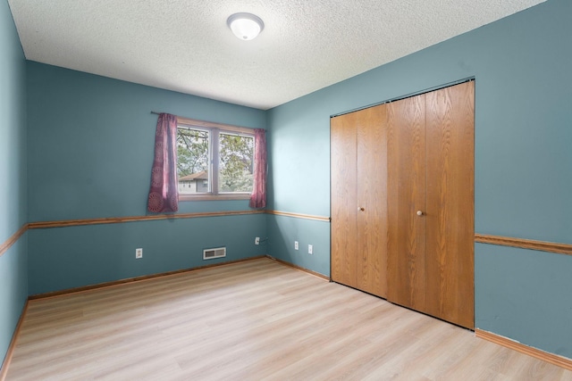 unfurnished bedroom featuring wood finished floors, a textured ceiling, and a closet