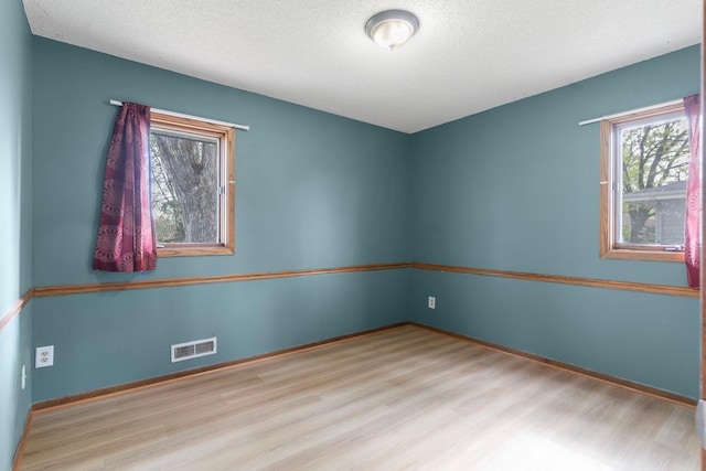 empty room featuring wood finished floors, baseboards, and a textured ceiling