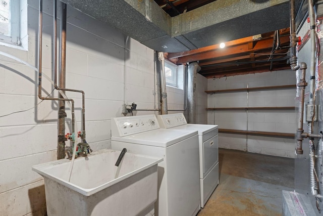 clothes washing area featuring separate washer and dryer and concrete block wall