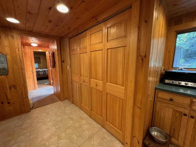 corridor with wooden walls, wood ceiling, light flooring, and recessed lighting