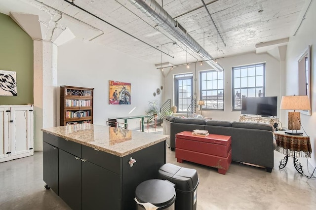 730 Stinson Blvd Unit 205, Minneapolis, MN 55413 - kitchen with finished concrete flooring, a kitchen island, dark cabinets, and light stone counters