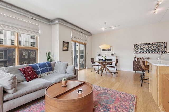 2845 Colfax Ave S Unit W202, Minneapolis, MN 55408 - living room featuring rail lighting, light wood-style flooring, bar, and baseboards