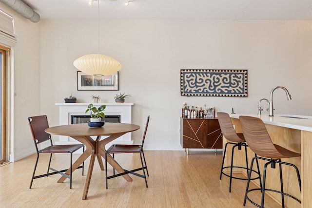 2845 Colfax Ave S Unit W202, Minneapolis, MN 55408 - dining space featuring light wood finished floors, bar with sink, a glass covered fireplace, and baseboards