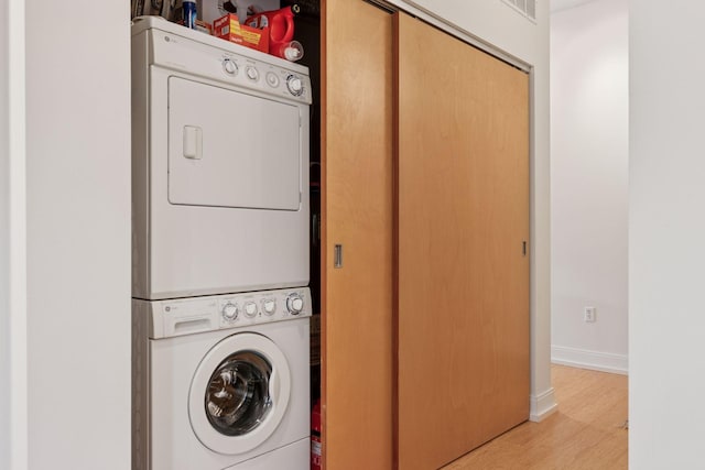 2845 Colfax Ave S Unit W202, Minneapolis, MN 55408 - clothes washing area featuring stacked washing machine and dryer, wood finished floors, and baseboards