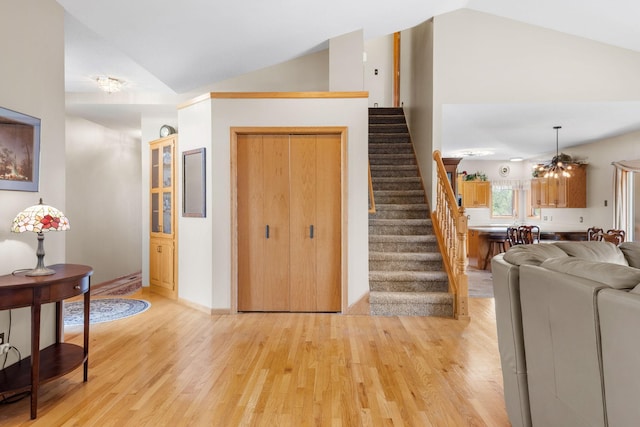 living area with lofted ceiling, stairs, light wood finished floors, and baseboards