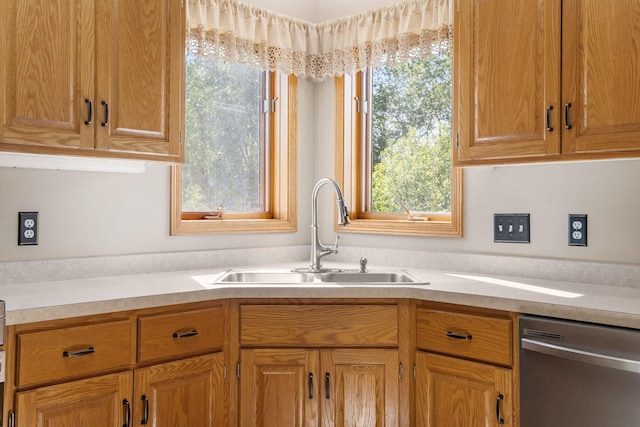 kitchen with stainless steel dishwasher, a sink, and light countertops