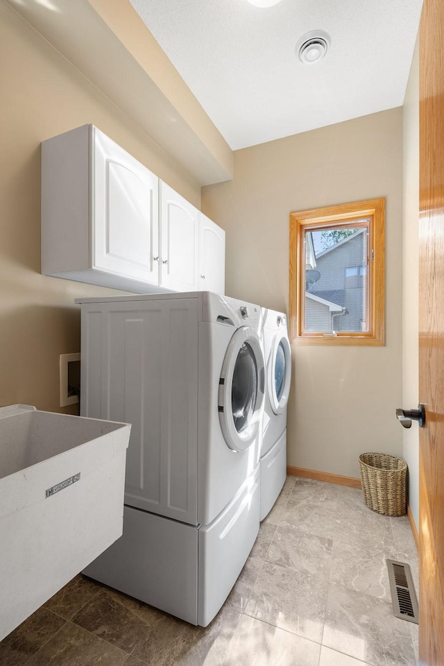 washroom featuring cabinet space, washing machine and dryer, and baseboards