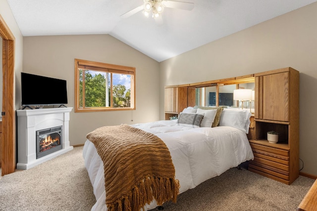 bedroom featuring carpet, vaulted ceiling, a ceiling fan, a glass covered fireplace, and baseboards