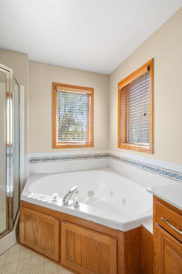 bathroom featuring a tub with jets, a shower stall, a textured ceiling, and tile patterned flooring