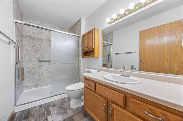 bathroom featuring toilet, wood finished floors, a shower stall, and vanity