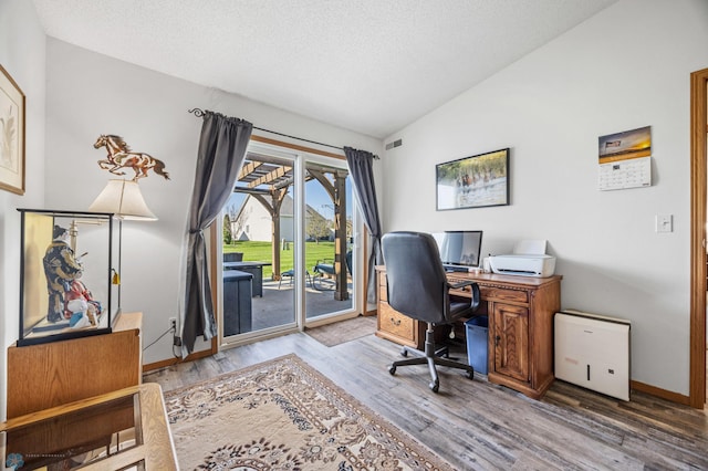 office featuring wood finished floors, vaulted ceiling, a textured ceiling, and baseboards