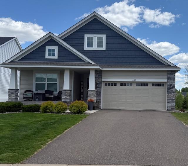 6168 Quenroe Ave NE, Otsego, MN 55330 - craftsman-style home with stone siding, a porch, asphalt driveway, a front yard, and an attached garage