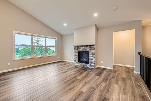 6168 Quenroe Ave NE, Otsego, MN 55330 - unfurnished living room with lofted ceiling, wood finished floors, a stone fireplace, and recessed lighting