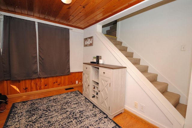 staircase featuring wood finished floors, wood ceiling, and baseboards