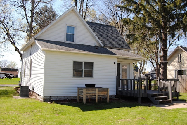 rear view of property with a wooden deck, central air condition unit, a yard, and roof with shingles